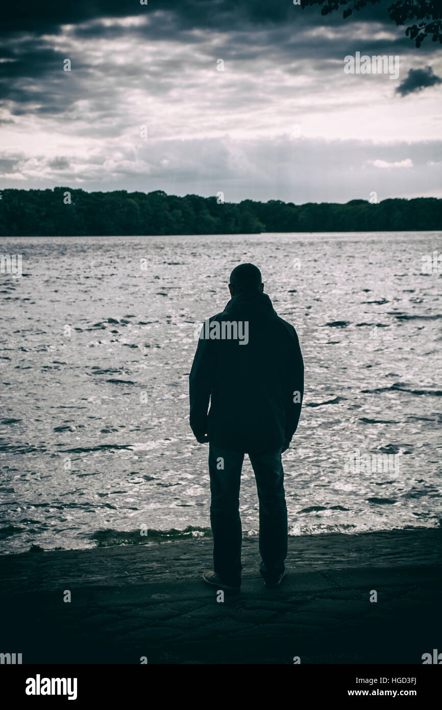 Silhouette di un uomo in piedi in riva al lago Foto Stock