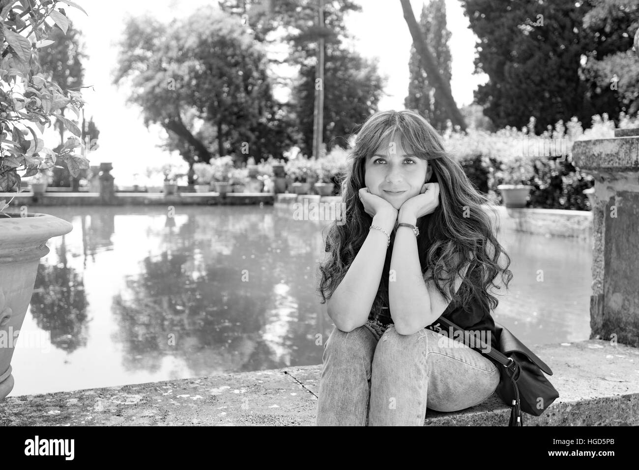 Bella ragazza con i capelli lunghi in posa in prossimità di un lago artificiale e un albero di limone Foto Stock