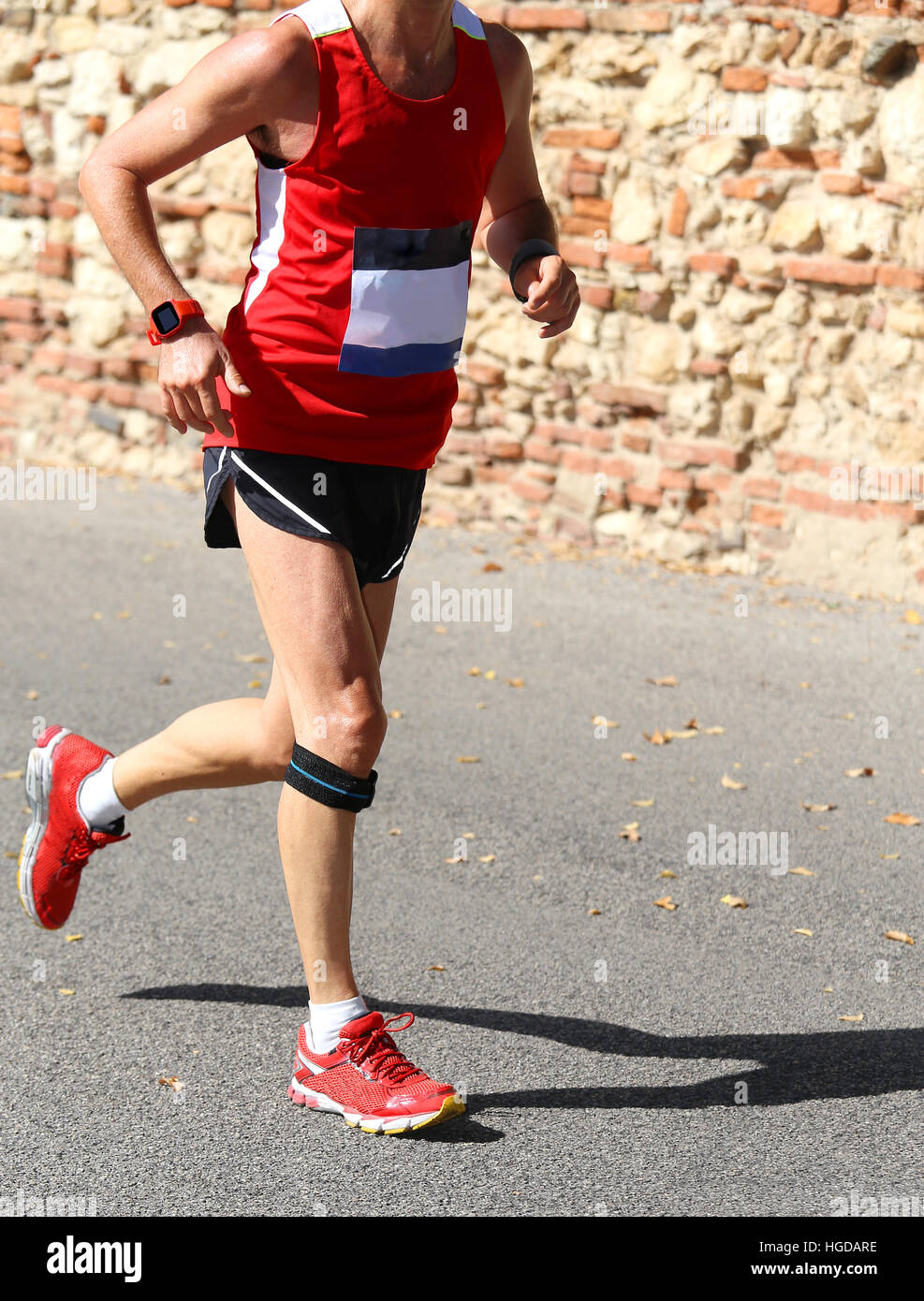 Runner corre con abbigliamento sportivo e una fascia elastica sotto il ginocchio Foto Stock