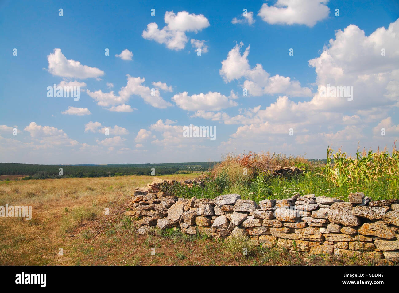 Paesaggio rurale, una recinzione fatta di pietra naturale, contro il cielo con le nuvole in estate Foto Stock