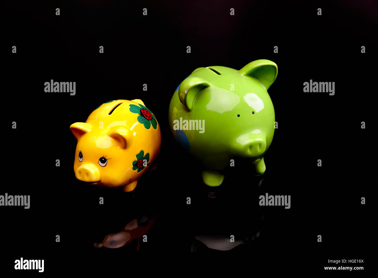 Yello e verde piggy banche su uno sfondo nero Foto Stock