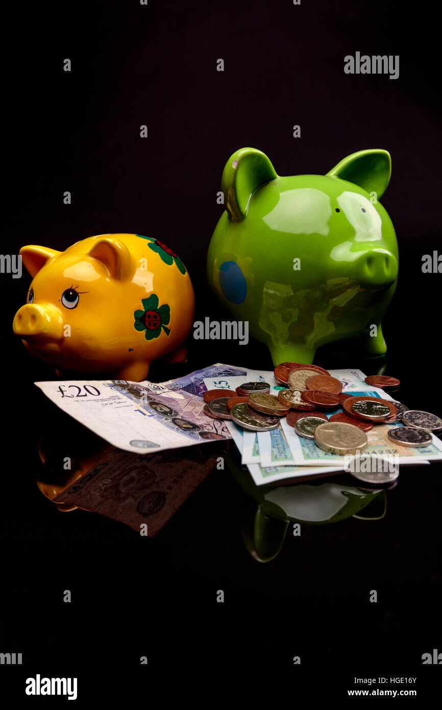 Yello e verde piggy banche su uno sfondo nero Foto Stock
