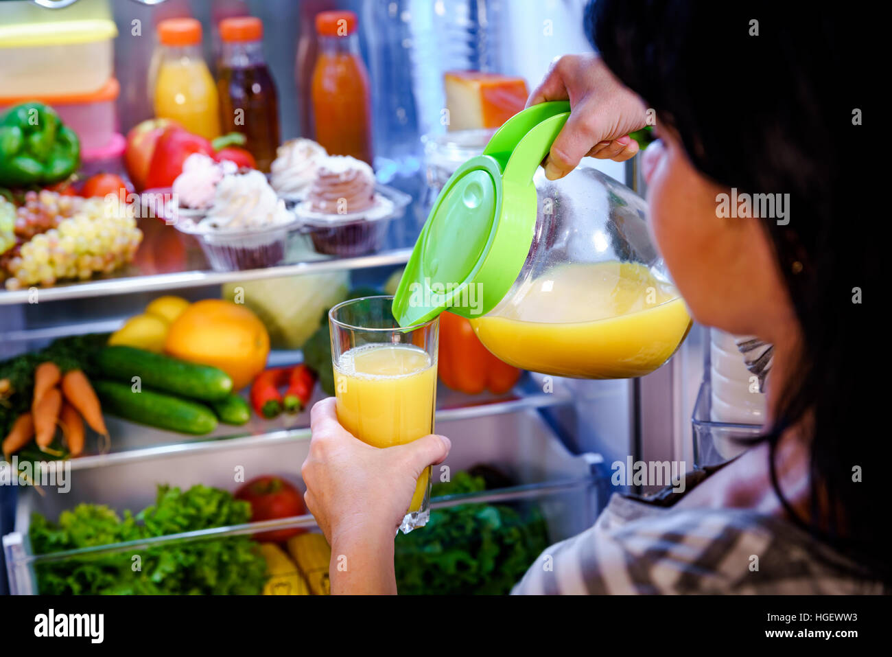 La donna prende il succo di arancia dal frigorifero aperto Foto Stock
