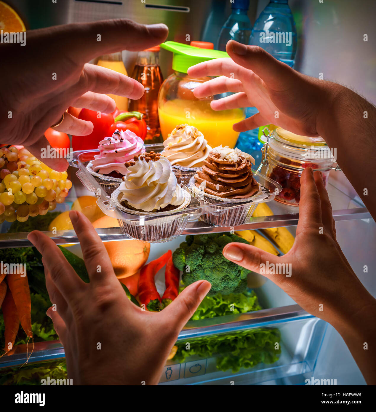 Le mani umane raggiungendo per la torta dolce di notte nel frigorifero aperto Foto Stock