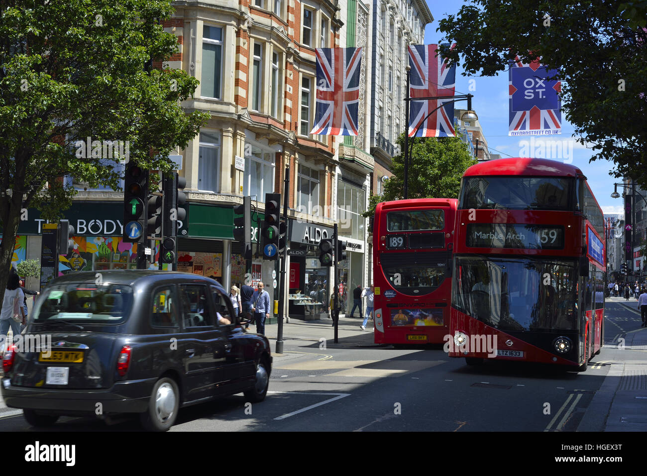 Oxford Street, Londra in estate. La strada è decorata con bandiere Union Jack, autobus rossi e taxi neri che si spostano lungo la strada. Foto Stock