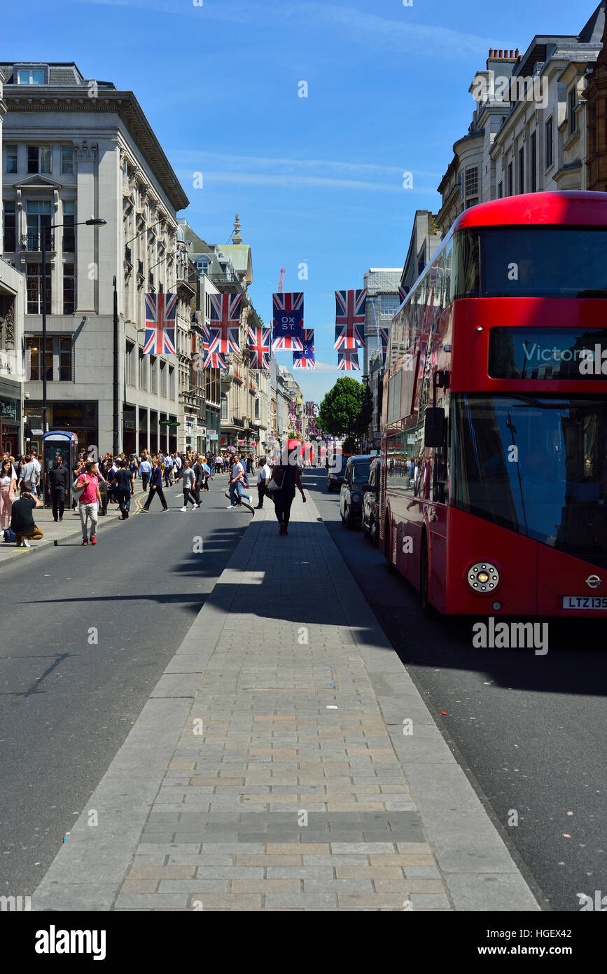 Oxford Street, Londra in estate. La strada è decorata con bandiere Union Jack, autobus rossi e taxi neri che si spostano lungo la strada. Foto Stock