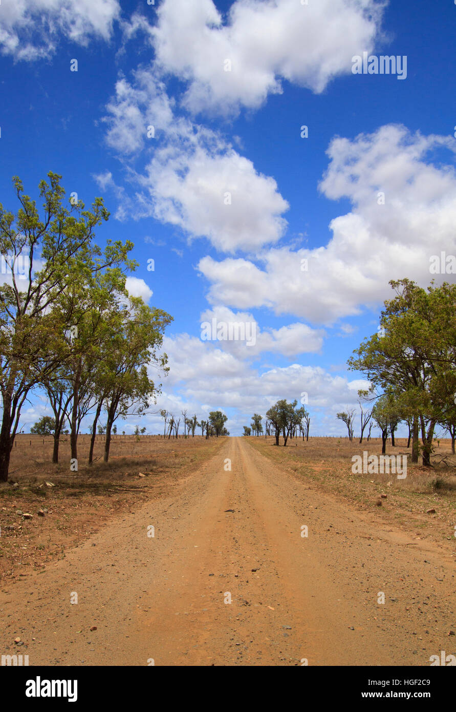 Un dissigillato strada rurale con cielo blu e nuvole in outback Queensland Australia Foto Stock