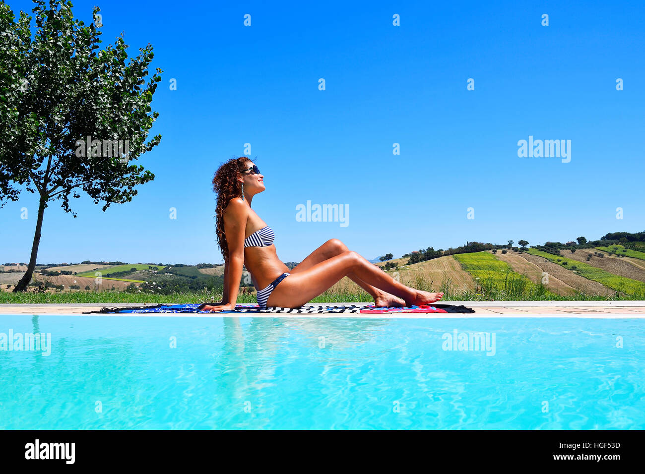 La donna a prendere il sole in bikini da un pool, Morro D'Alba, Ancona, Marche, Italia Foto Stock