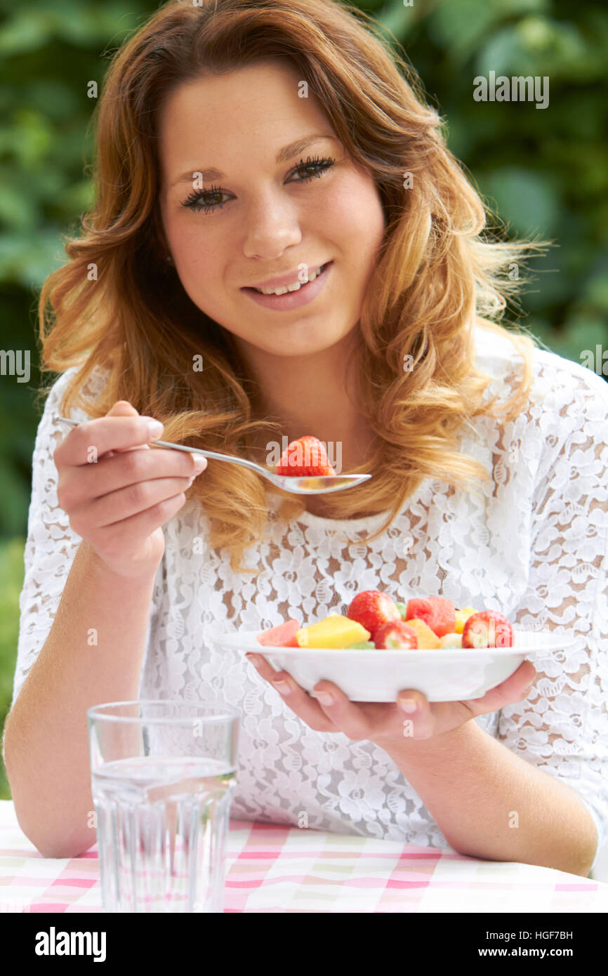 Ragazza adolescente mangiar sano ciotola di insalata di frutta Foto Stock