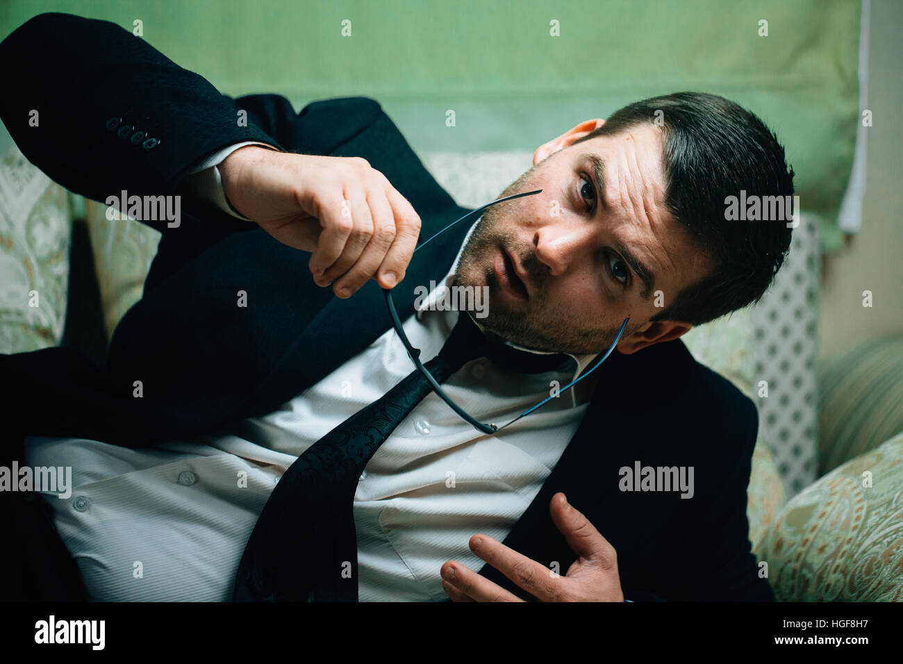 Imprenditore prende gli occhiali da sole e orologi sdraiato sul lettino Foto Stock