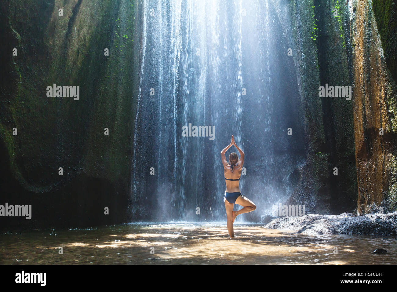 Lo yoga, bella donna pratiche in cascata, il corpo e la mente in armonia in natura Foto Stock