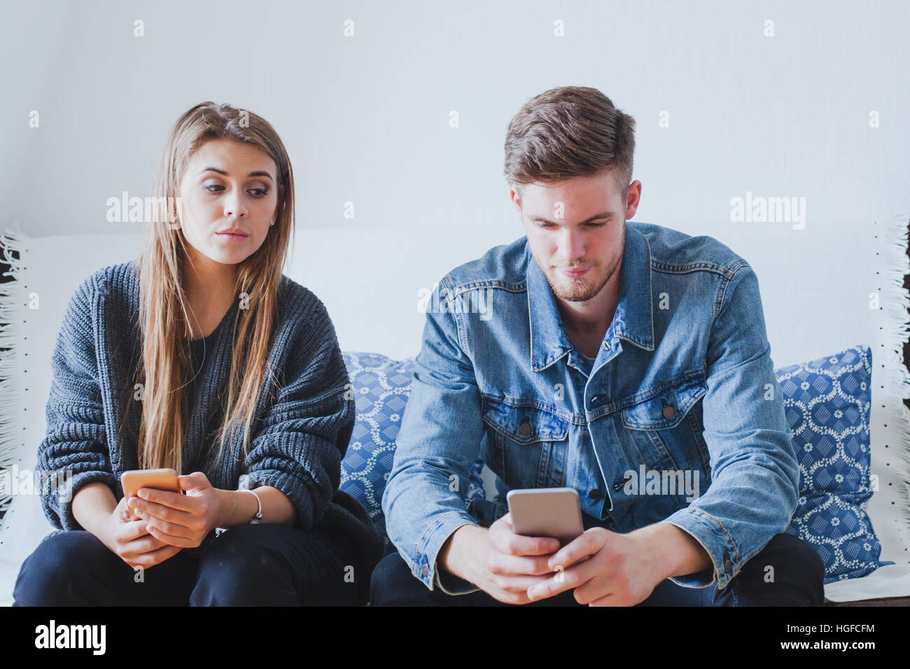 Gelosa moglie spionaggio marito, sospetti ragazza cercando di leggere i messaggi di posta elettronica sul telefono cellulare del fidanzato mentre non sta a guardare Foto Stock