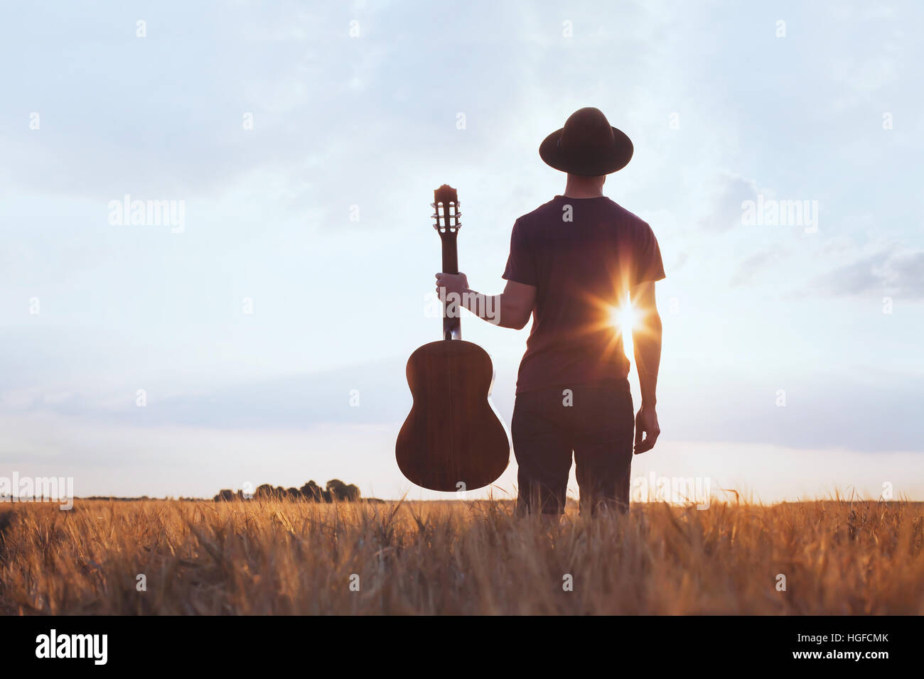 Festival della musica di sottofondo, silhouette di musicista artista con la chitarra acustica al tramonto campo Foto Stock