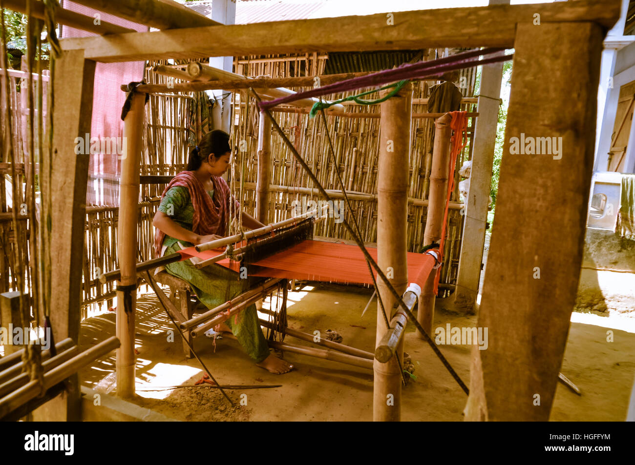 Srimongal, Bangladesh - circa il luglio 2012: giovane nero dai capelli donna si siede e tesse su un semplice telaio in legno in Srimongal, Bangladesh. Documentario Contatti Foto Stock