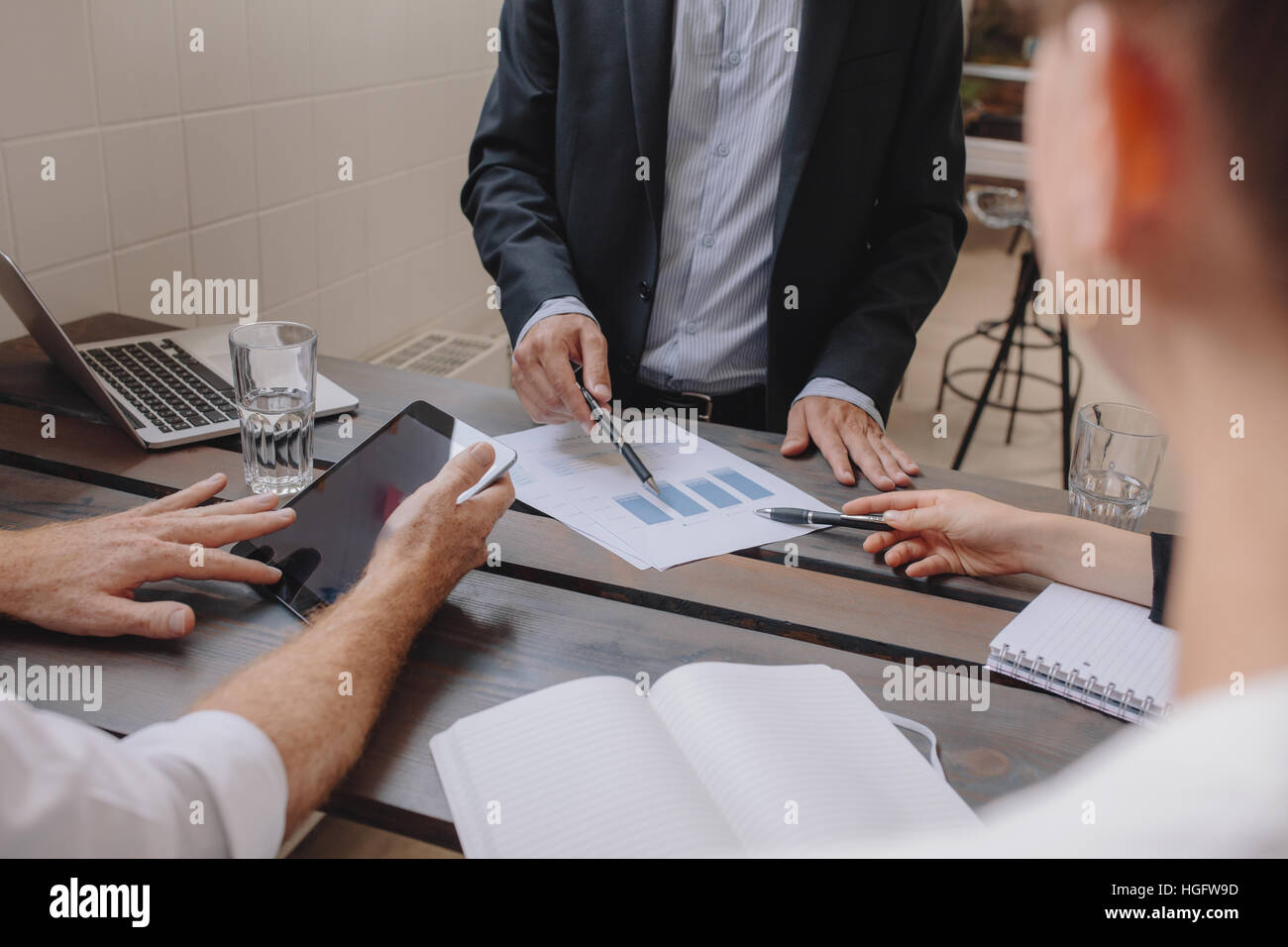 Immagine ravvicinata di team di professionisti riuniti con tavoletta digitale e grafici. La gente di affari per discutere il piano finanziario. Le mani umane puntando al grap Foto Stock