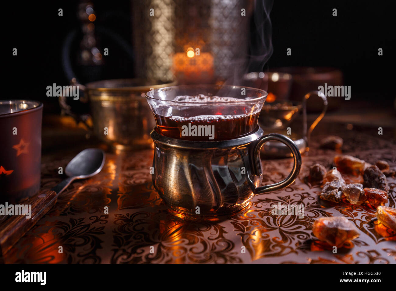 Il tè nero in un bicchiere di vetro a lume di candela Foto Stock