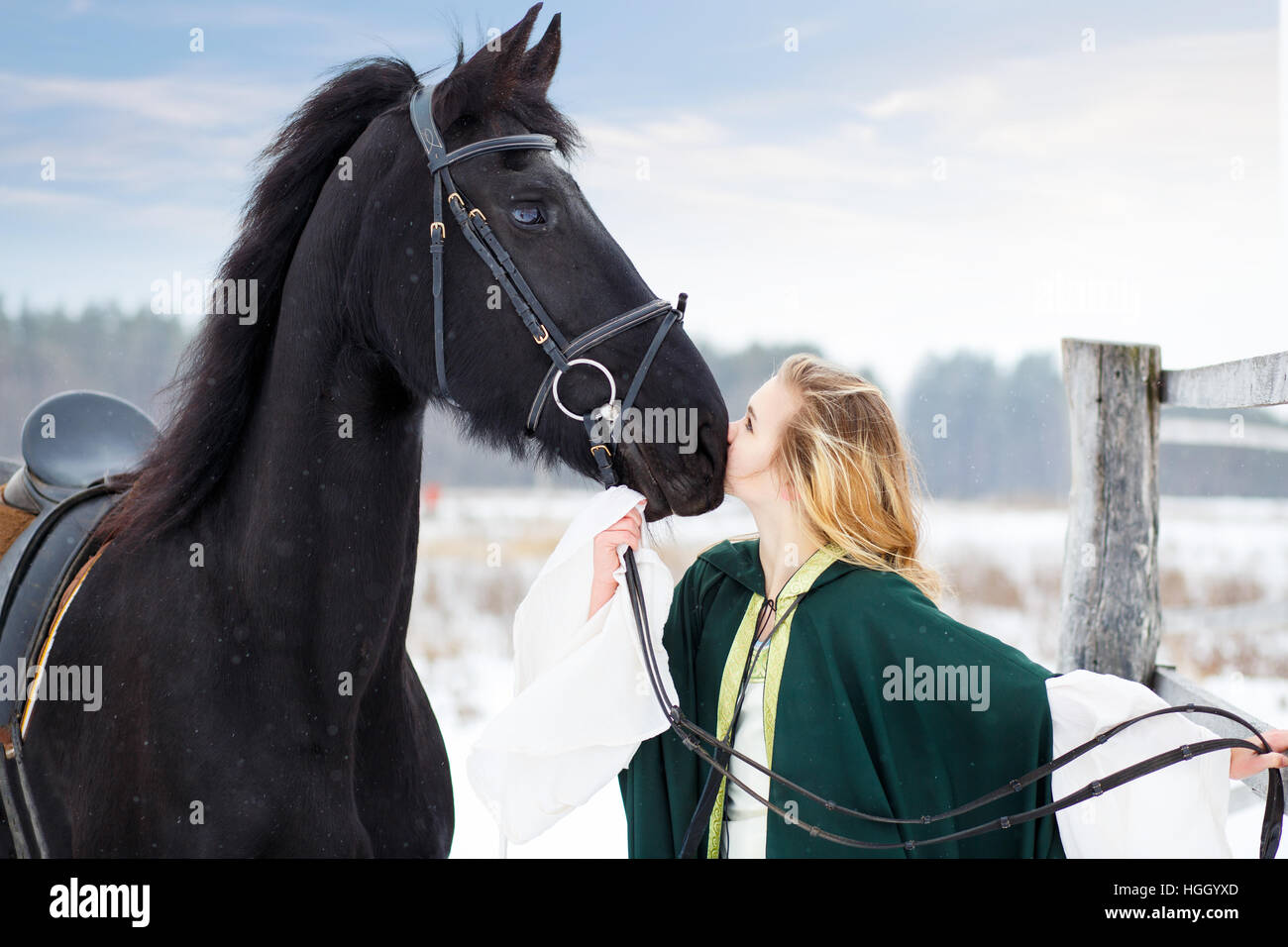Giovane ragazza in abito con cavallo nero in inverno Foto Stock