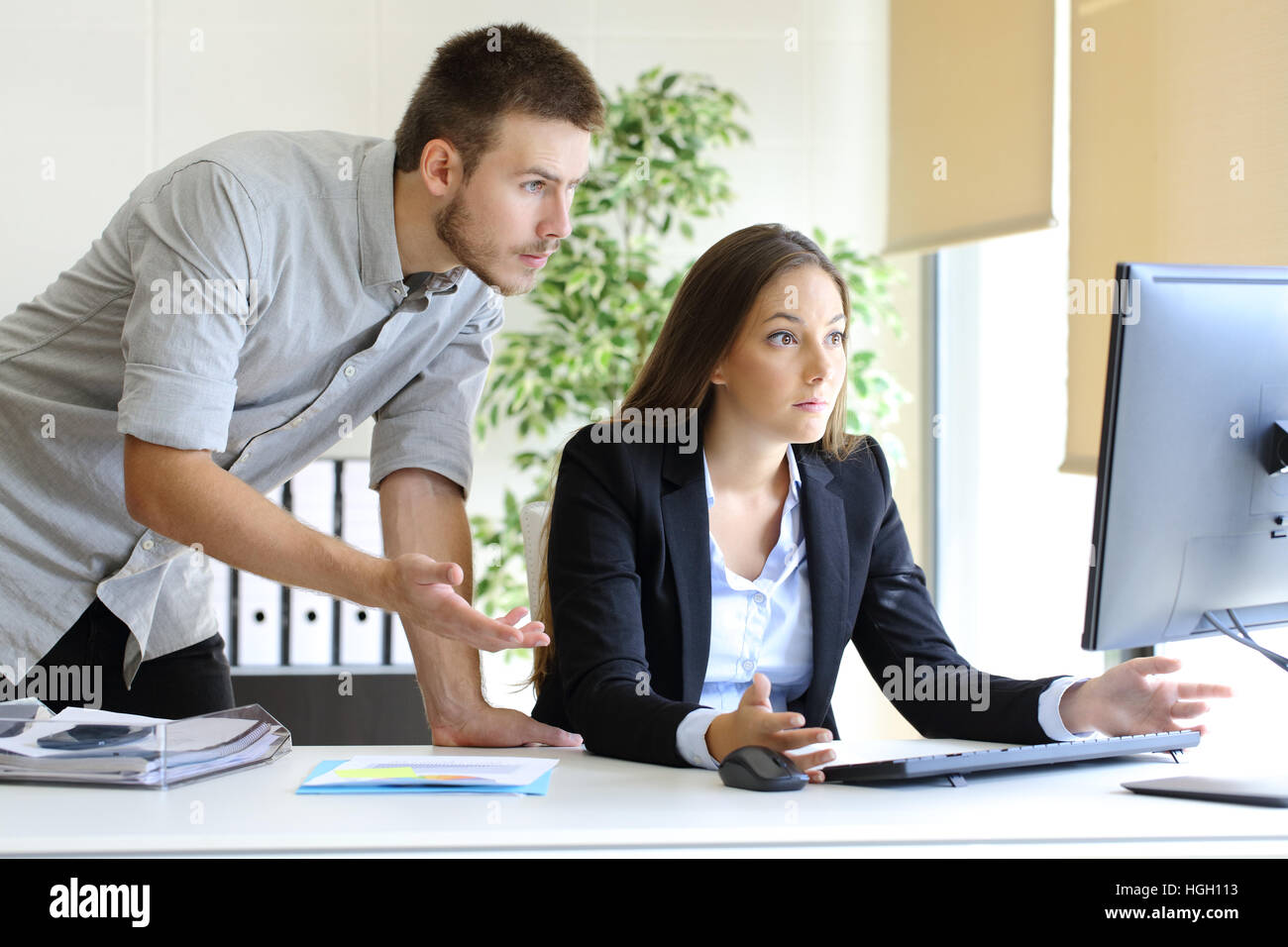Turbare gli imprenditori cercano di lavorare in linea con un computer desktop guardando il monitor in ufficio Foto Stock