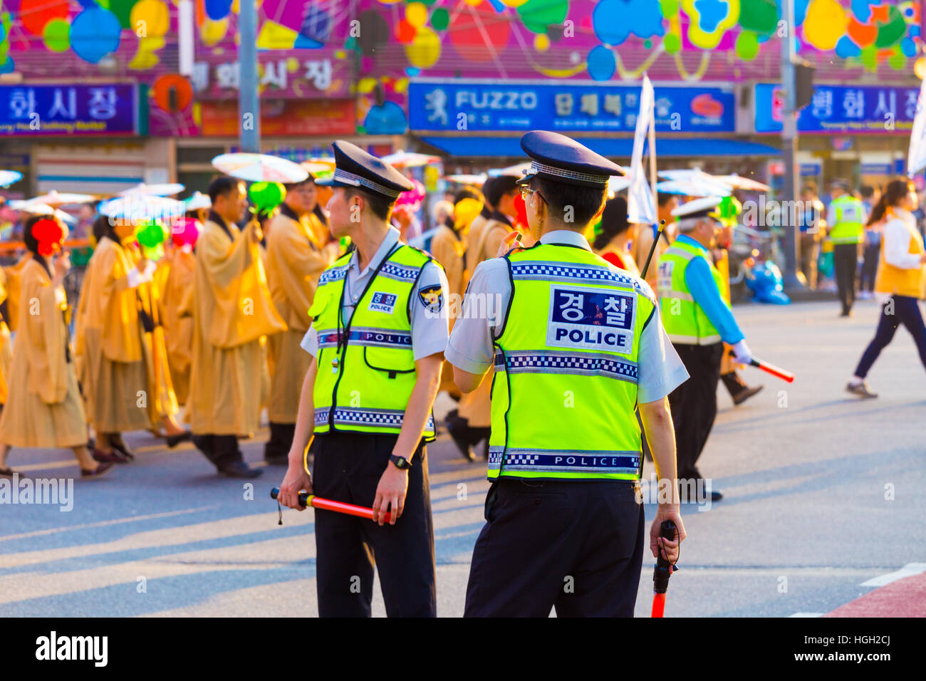 Street contestatori dietro due poliziotti coreani nel giubbotto luminoso uniforme, polizia scritto sul retro e la supervisione di una protesta pacifica su Foto Stock
