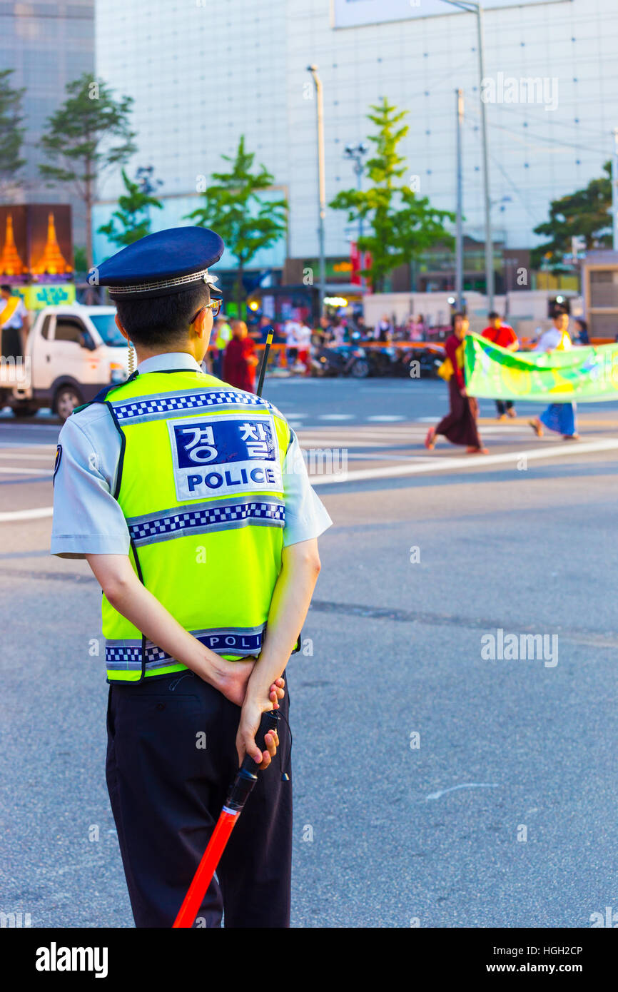 Parte posteriore del maschio poliziotto coreano in uniforme dirigere traffico durante la protesta pacifica marzo nel centro cittadino Foto Stock