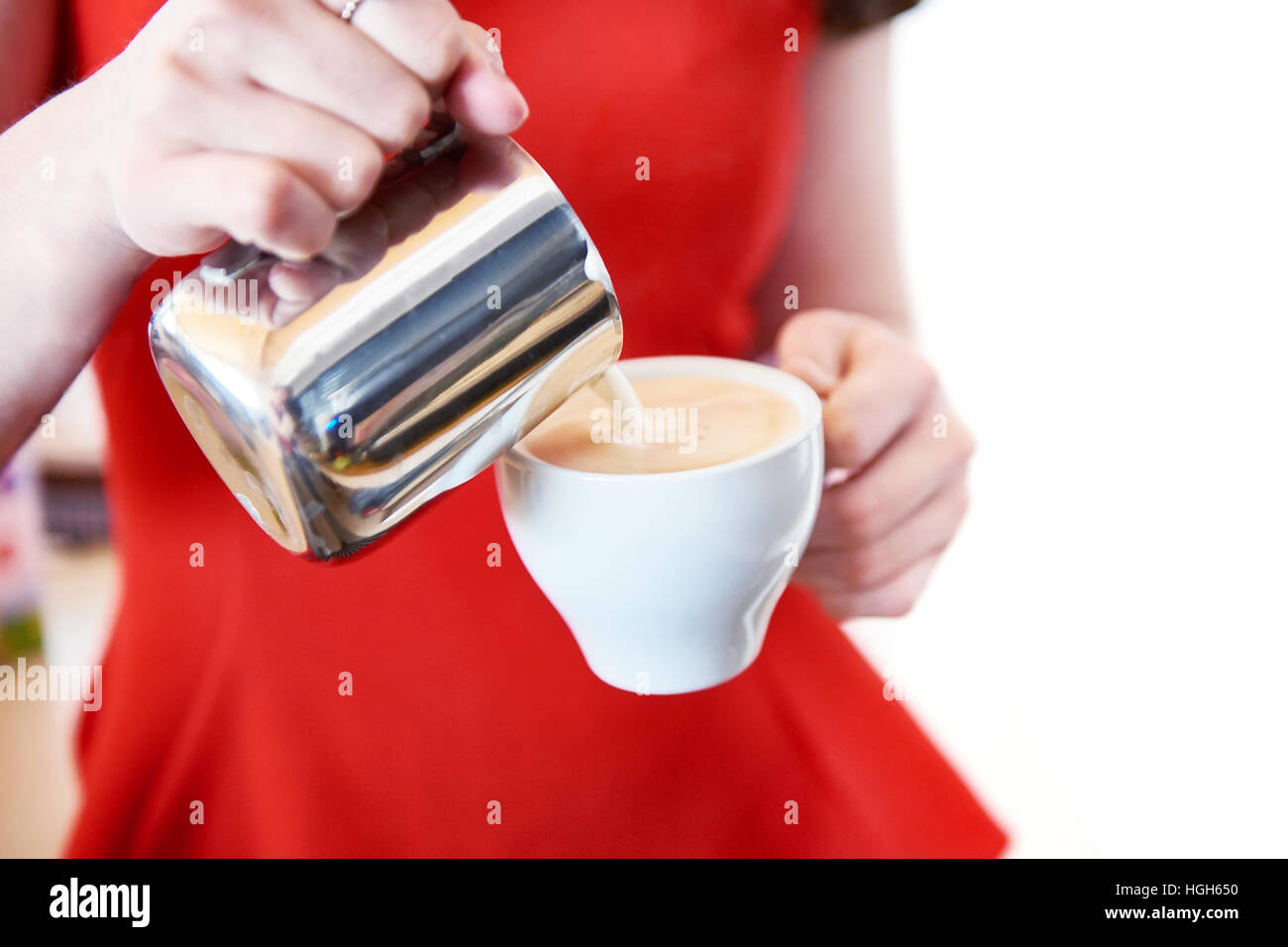 Ragazza in rosso è di preparare un cappuccino in un caffè bar Foto Stock