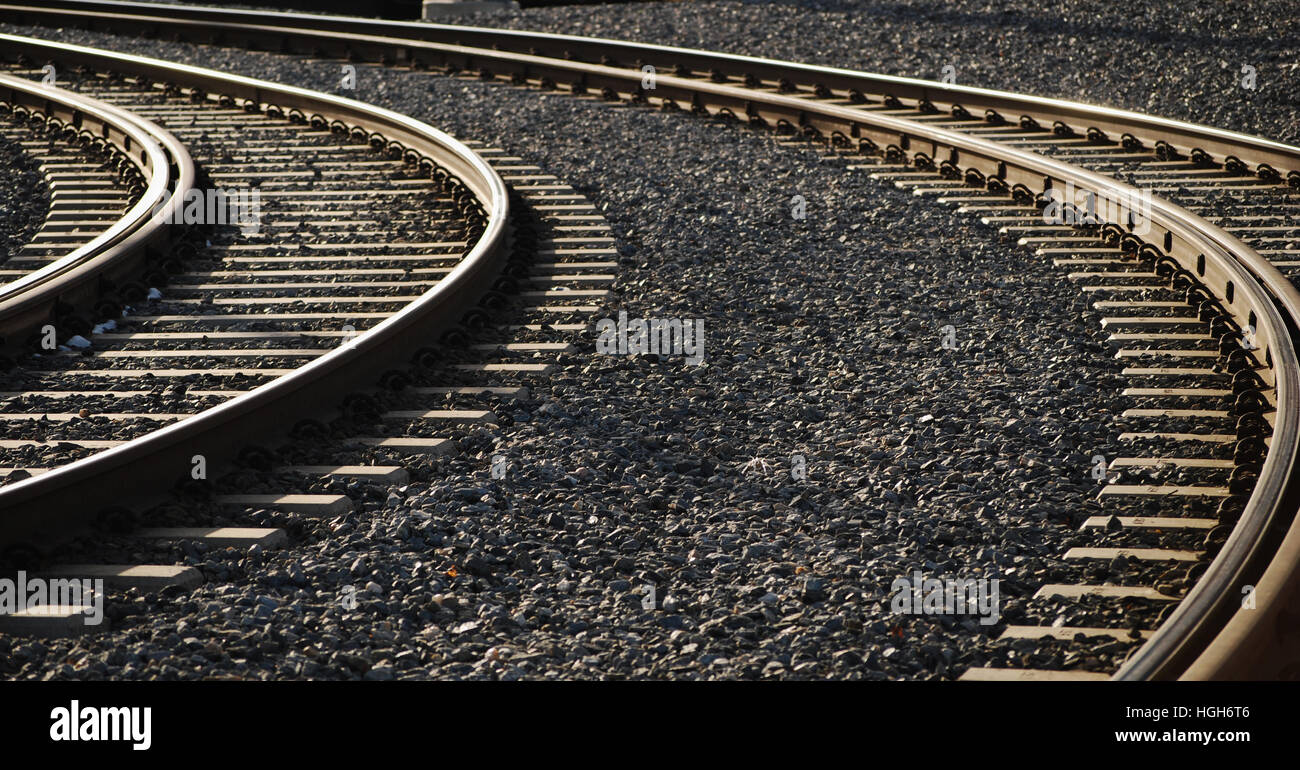 Binari del treno che corre attraverso la parte industriale della città. In bianco e nero. Foto Stock