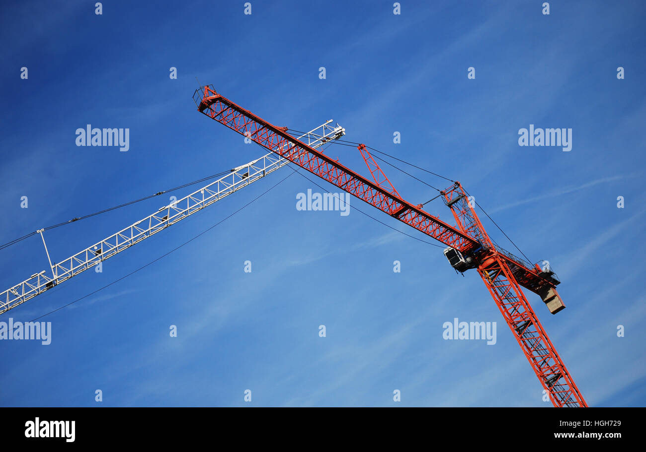 Due gru a torre edificio in un sito di costruzione contro il cielo blu. Foto Stock