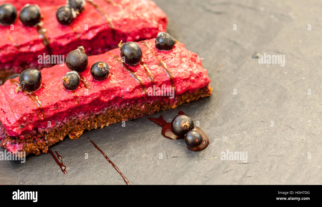 Materie cioccolato torta di frutti di bosco con i frutti di bosco e lo sciroppo al cioccolato e ribes. Amore per un sano cibo crudo concetto. Foto Stock