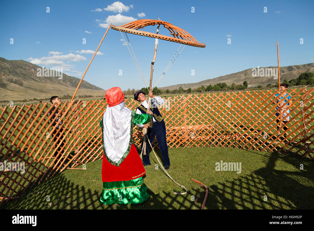 Popolo nomade in costumi nazionali la costruzione di una yurta e trattenere la corona della cupola di yurta noto come Shangyrak Shanyrak o. Foto Stock