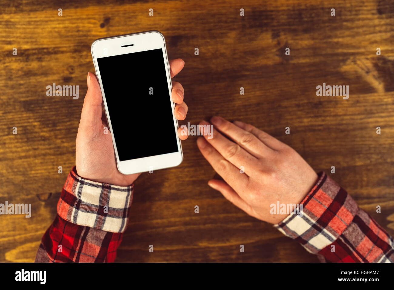 Mock up vuoto mobile smart phone schermo in mani femminili sopra scrivania da ufficio, vista dall'alto Foto Stock