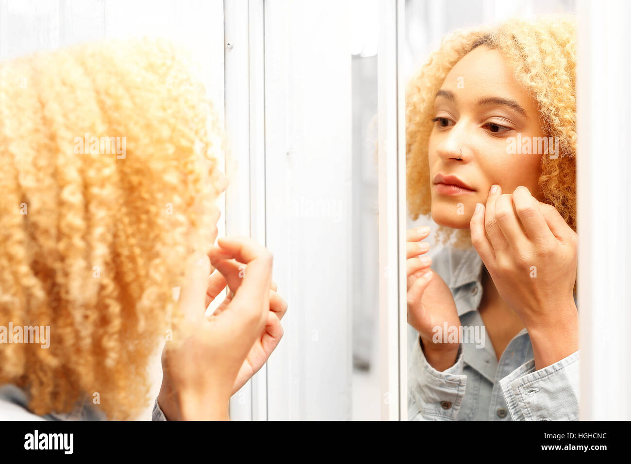 Prima le rughe. L'invecchiamento della pelle. Donna guarda nello specchio guardando i primi segni di invecchiamento. Foto Stock