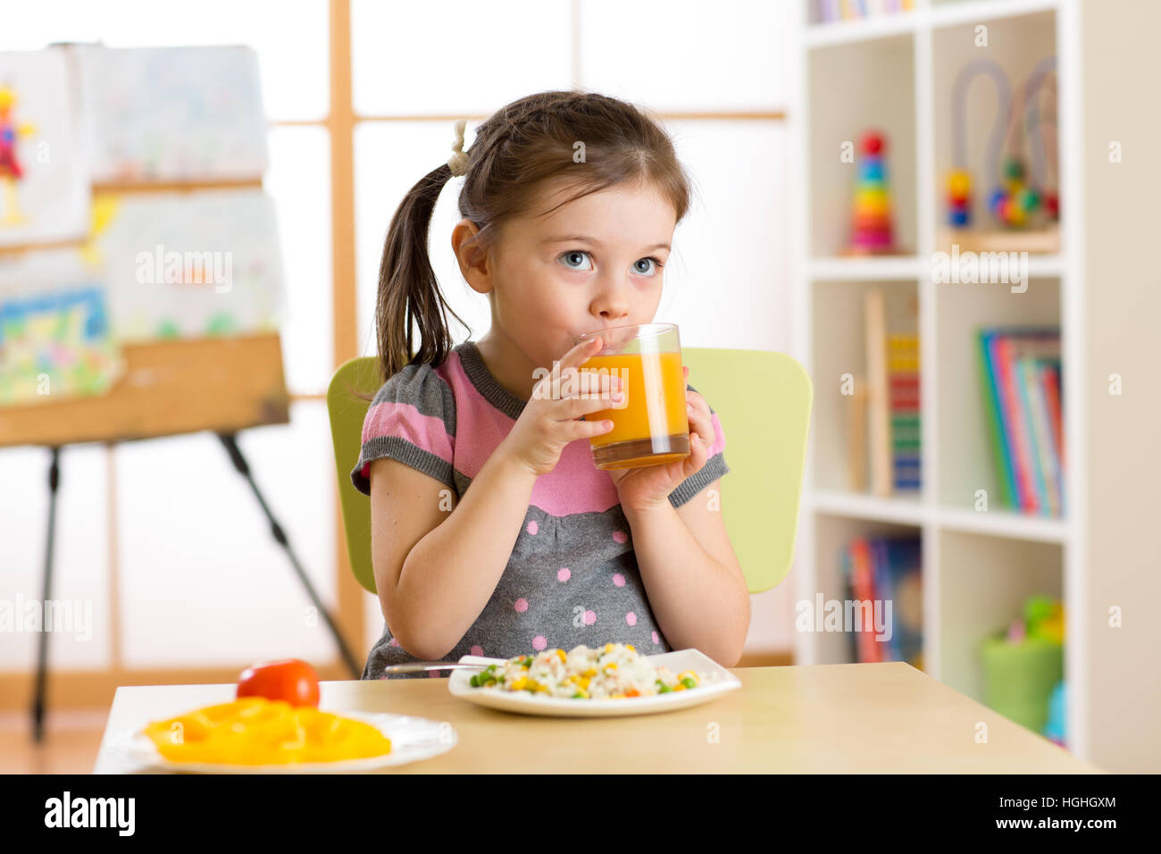 Bella ragazza bambino bere e mangiare cibo sano nella scuola materna Foto Stock