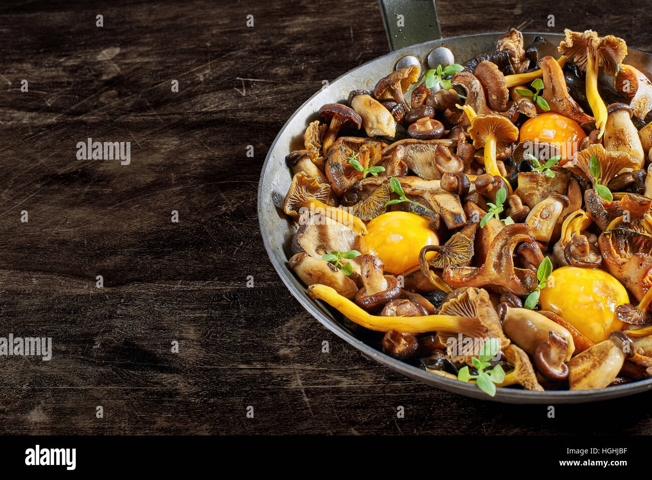 Padella in acciaio con (funghi shiitake, giallo piede, funghi porcini, zafferano e Milkcap chanterelle nero) e morbidi i tuorli. Foto Stock