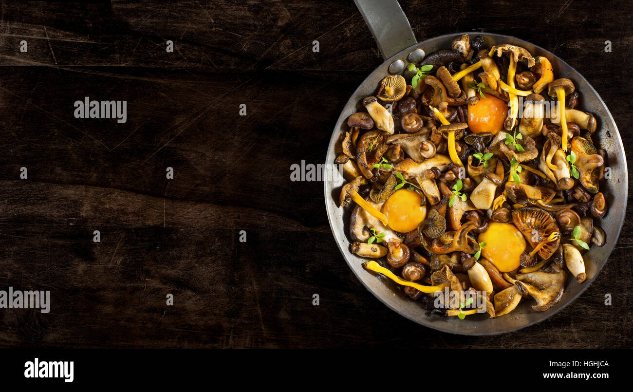 Padella in acciaio con (funghi shiitake, giallo piede, funghi porcini, zafferano e Milkcap chanterelle nero) e morbidi i tuorli. Foto Stock