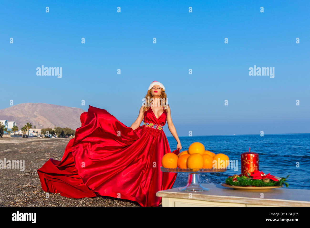 Bella donna in abito rosso festeggia il nuovo anno in riva al mare Foto Stock