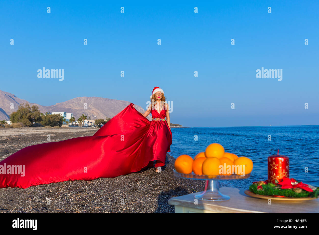 Bella donna in abito rosso festeggia il nuovo anno in riva al mare Foto Stock