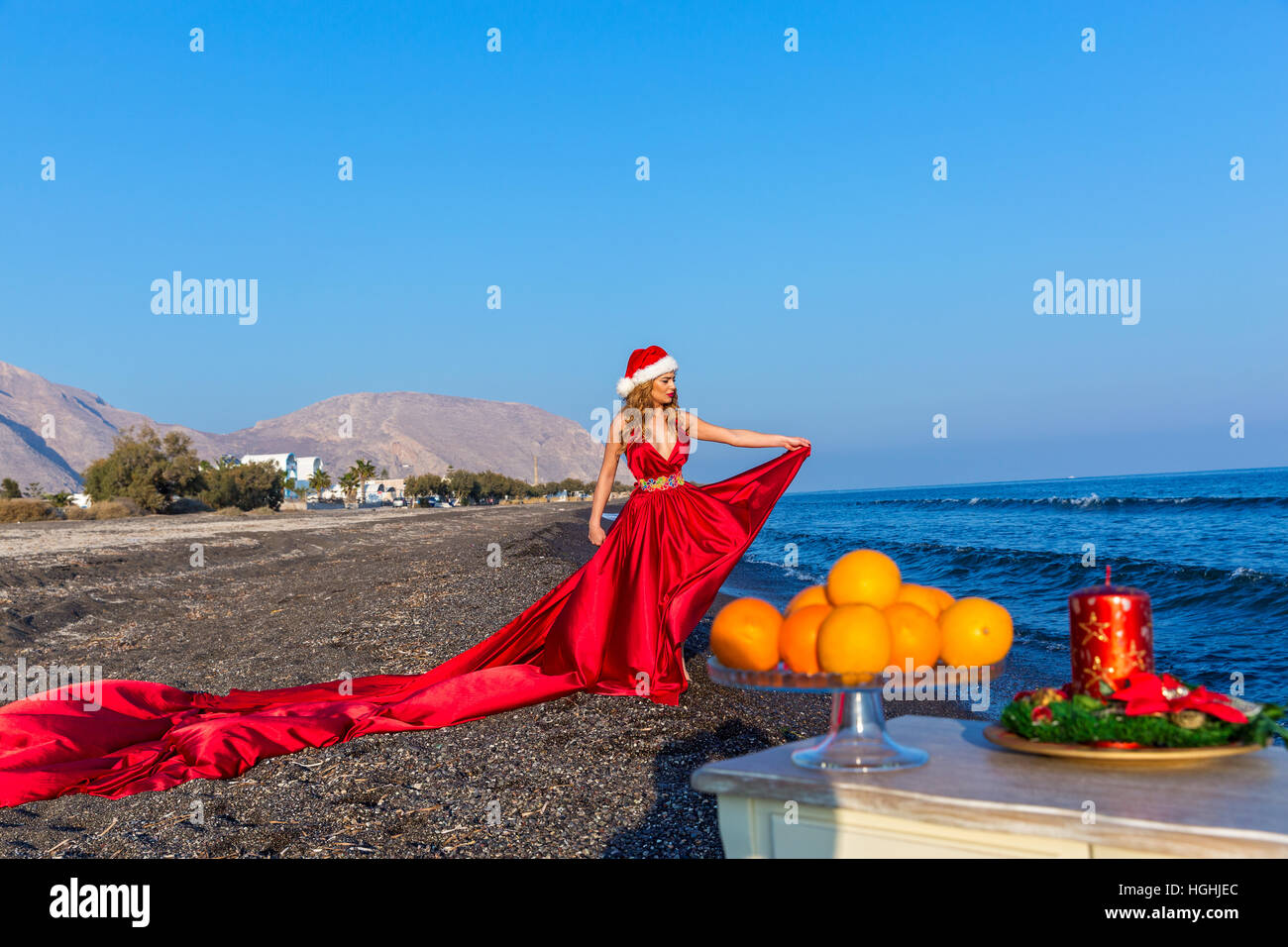Bella donna in abito rosso festeggia il nuovo anno in riva al mare Foto Stock