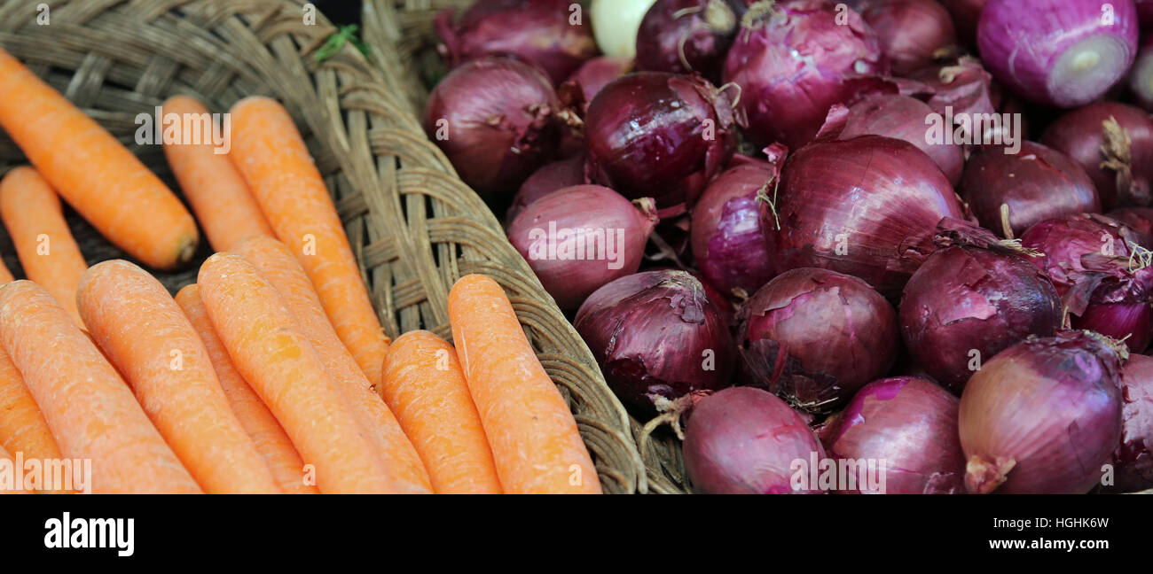 Cestello di arancio di carote e cipolle rosse per la vendita presso il fruttivendolo Foto Stock