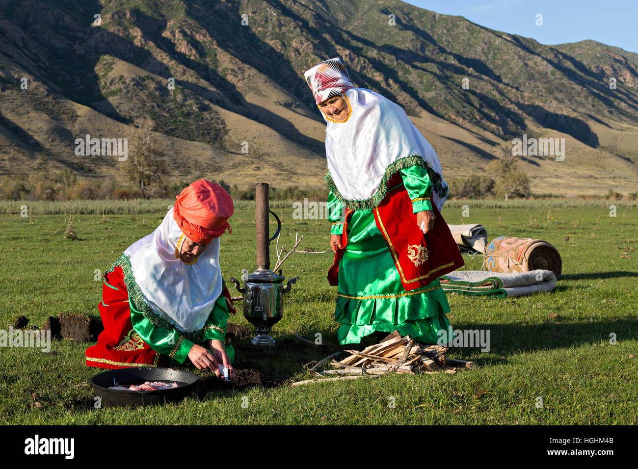 Il kazako donne in costumi nazionali cucinare all'aperto, nel villaggio di soggiornare, Kazakistan Foto Stock
