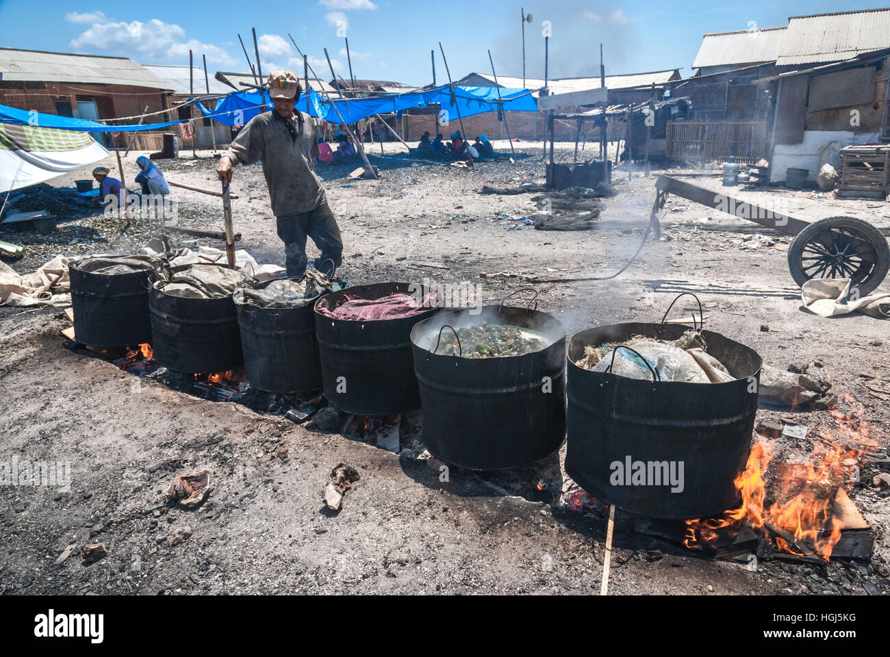 Un uomo che fa bollire cozze verdi al centro dell'industria locale del pesce nella zona costiera di Giacarta, Indonesia. Foto Stock