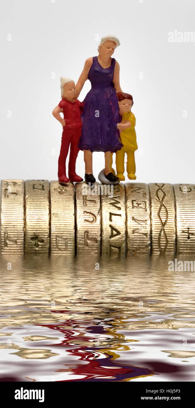 Madre e due bambini in piedi sulla parte superiore di alcuni inglesi una libbra di monete Foto Stock