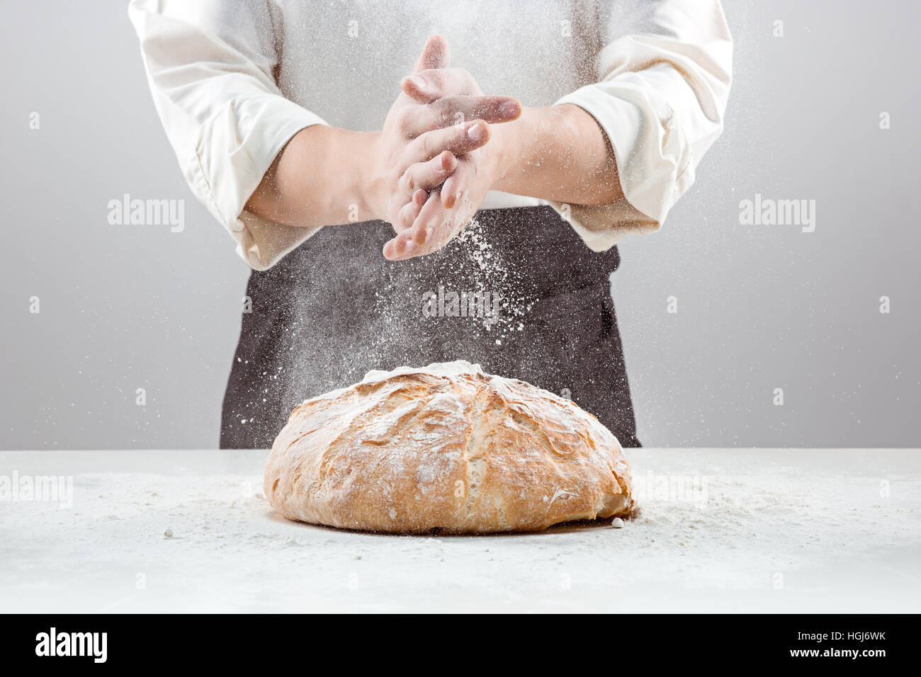 Il maschio le mani nella farina e organico rustico pagnotta di pane Foto Stock