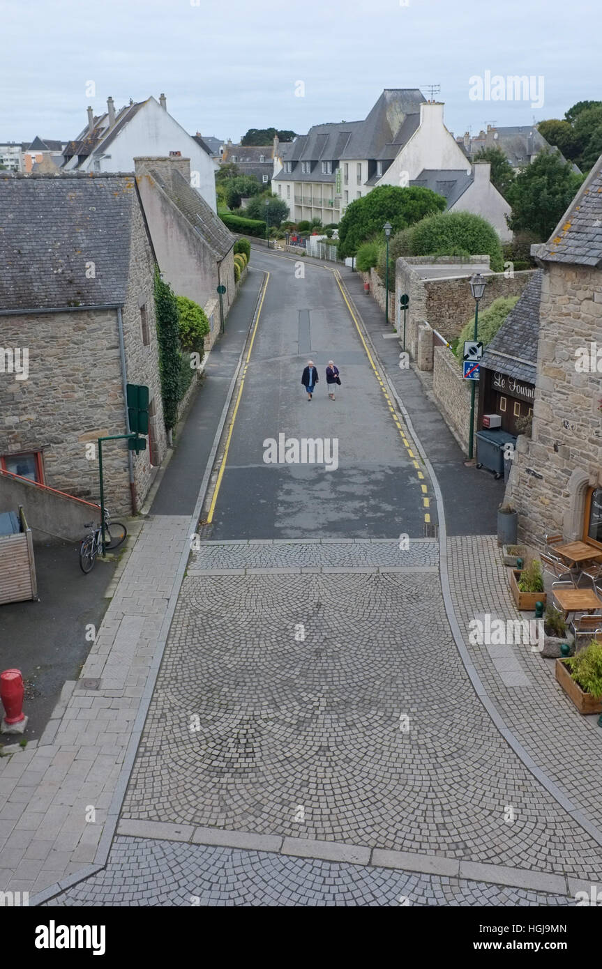 Due persone a piedi giù per una strada vuota a Roscoff, Brittany, Francia. Foto Stock
