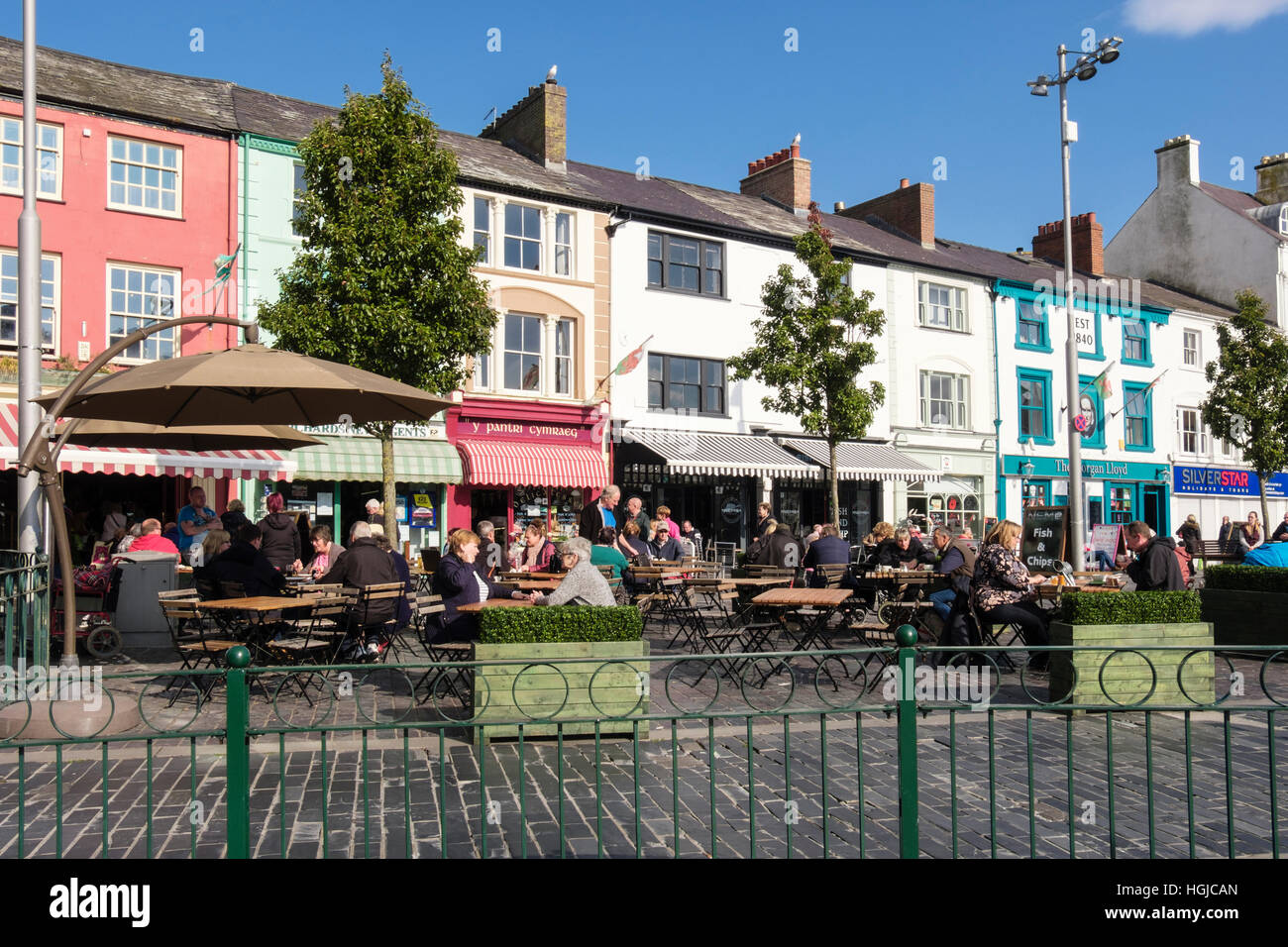 Persone per mangiare fuori nel sole in piazza street cafe. Caernarfon, Gwynedd, il Galles del Nord, Regno Unito, Gran Bretagna Foto Stock
