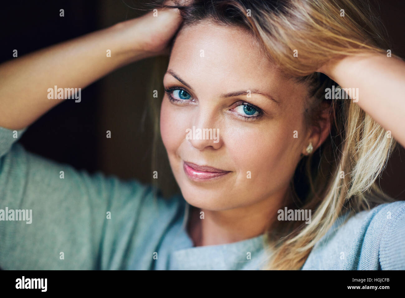 Bella Donna sorridente con le mani nei capelli Foto Stock