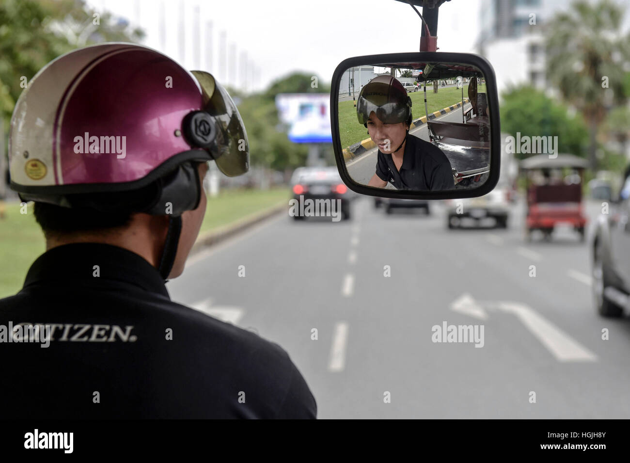 Un Tuk Tuk driver con casco Guardando nello specchietto retrovisore, Phnom  Penh Cambogia Foto stock - Alamy