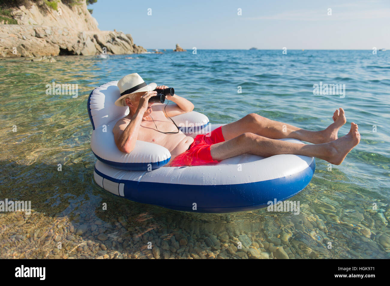 L'uomo anziano con spy occhiali galleggianti sulla sedia in mare Foto Stock
