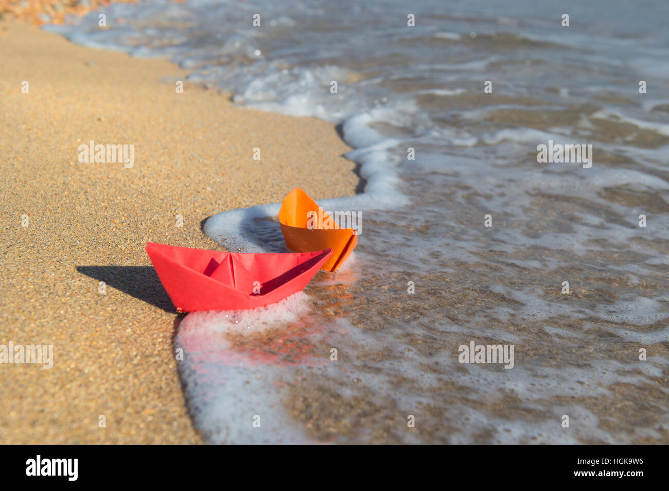 Due barche di carta in spiaggia a giocare con Foto Stock