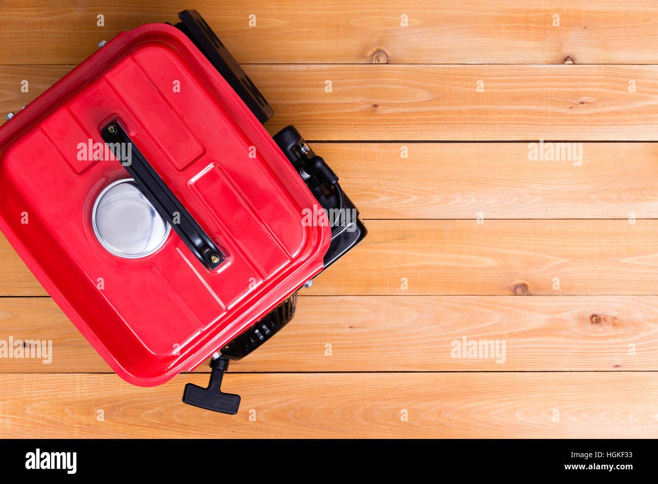 Rosso benzina generatore azionato visto dal di sopra su sfondo di legno con spazio di copia Foto Stock