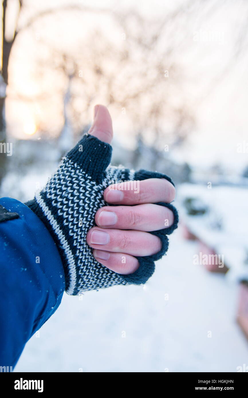 Maschio lato che mostra i pollici fino a guanti invernali all'aperto Foto Stock